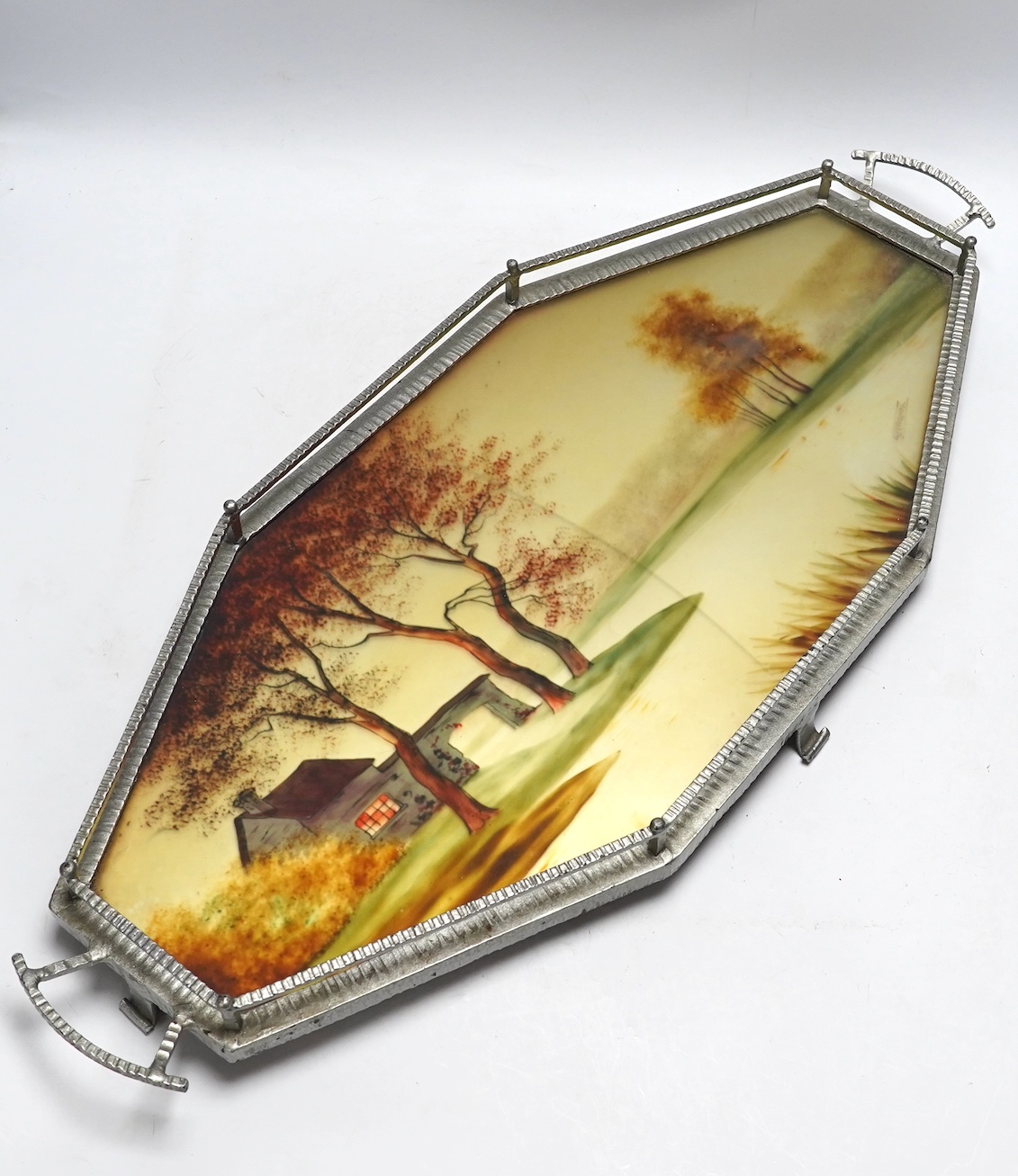 An Art Deco reverse painted and wrought iron tray, with a gallery, centered with a reverse painted landscape scene, signed 'Germonde', 70cm. Condition - damaged